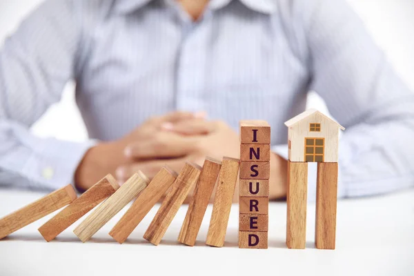 Unternehmer und Holz-Dominostein mit Wort versichert und Wohnmodell, Versicherungskonzept — Stockfoto