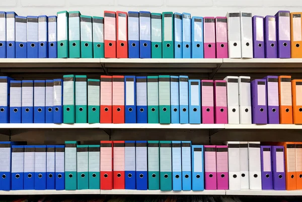colorful ring binder folder on white shelves, office stationary