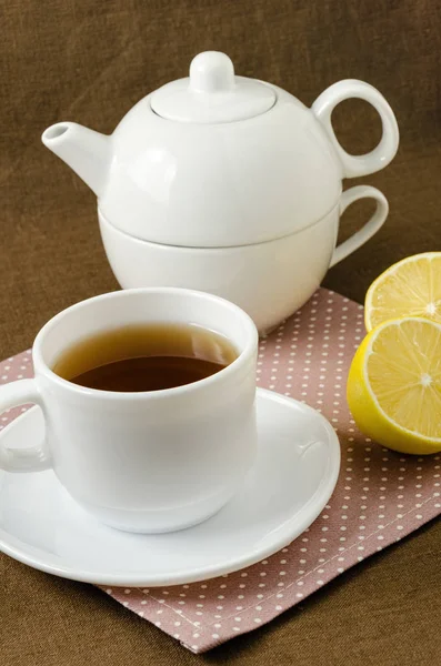 En la taza de servilleta de té con limón en platillo y tetera — Foto de Stock