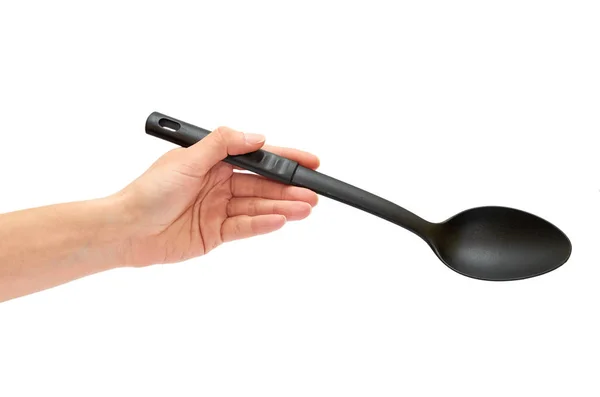 Vrouwelijke hand met een zwarte plastic lepel voor het koken van voedsel — Stockfoto