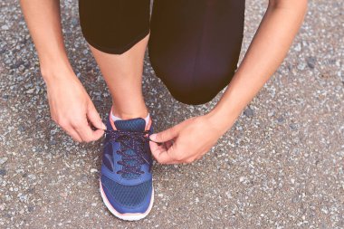 Kız koşu, bacaklar ve spor ayakkabı, tonlu görüntü sırasında yolda spor ayakkabı bağcıkları bağları