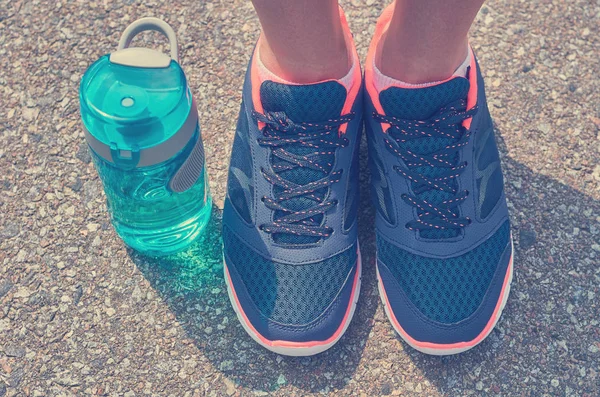 Spor şişe ve spor ayakkabılar bacaklar yola duruyor