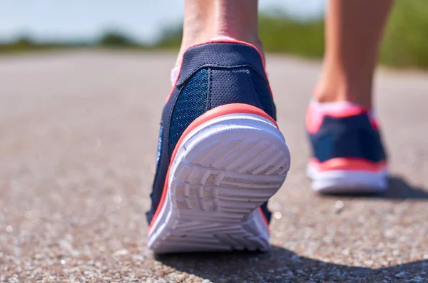 Νεαρή κοπέλα σε παπούτσια για τρέξιμο τρέχει κατά μήκος του δρόμου, εμφανίζονται μόνο τα πόδια της — Φωτογραφία Αρχείου