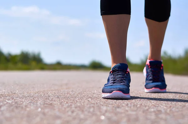 Νεαρή κοπέλα σε παπούτσια για τρέξιμο τρέχει κατά μήκος του δρόμου, εμφανίζονται μόνο τα πόδια της — Φωτογραφία Αρχείου