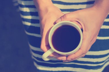 Parkta bir bankta oturan kız ve bir fincan aromalı kahve tutar. İş ya da çalışmalar bir mola sırasında görüntü tonda