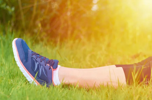 Jambes avec des baskets sportives filles sur une pelouse verte. Le concept de loisirs et de sport, la lumière du soleil — Photo