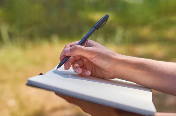 Το κορίτσι γράφει σε ένα σημειωματάριο και σπούδαζε στη φύση. Η έννοια της ελευθερίας και της ενότητας — Φωτογραφία Αρχείου