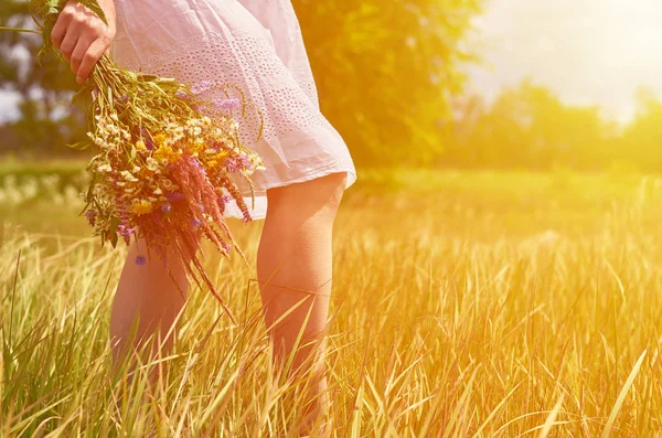 自分たちの手で野生の花の束とフィールドの女の子。純度と自然、日光と統一の概念 — ストック写真