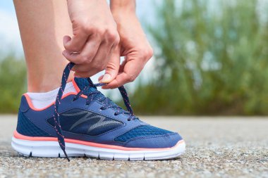 Kız süre koşu, bacaklar ve spor ayakkabı ayakkabı bağcığı yolda spor ayakkabı bağları