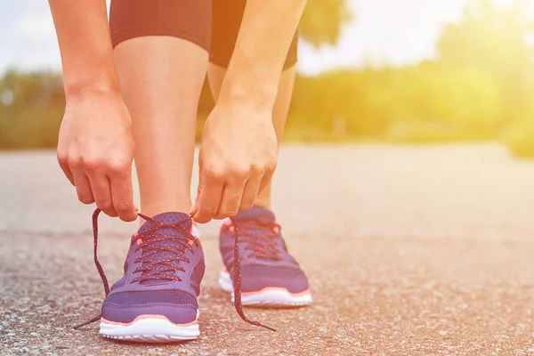 Kız süre koşu, bacaklar ve spor ayakkabı ayakkabı bağcığı yolda spor ayakkabı bağları