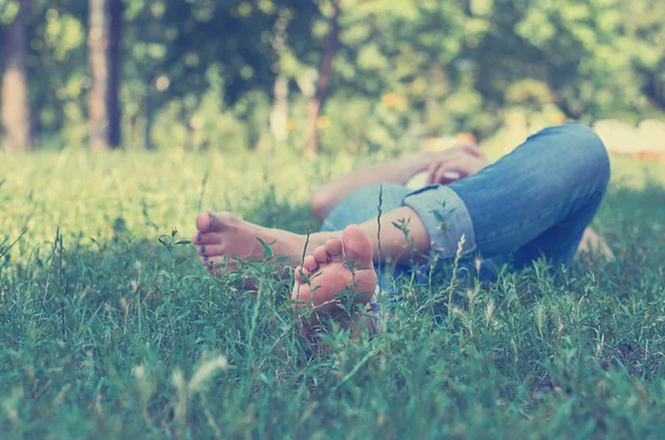 Egy fiatal lány feküdt a füvön, a parkban, és a pihenés. Koncepció, kültéri szabadidő, serenity — Stock Fotó