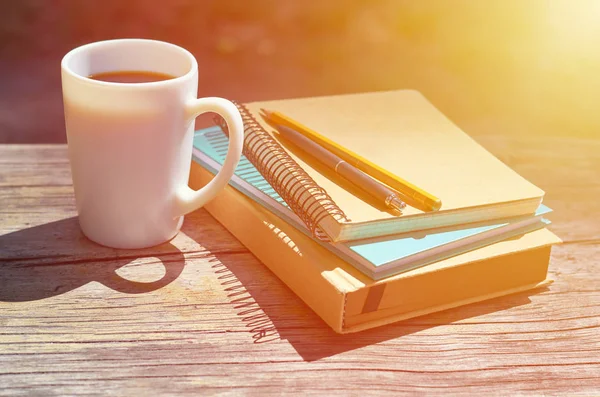 Una taza de café en un banco del parque. Cuadernos para escribir y libros. Estudios, trabajo y concepto empresarial —  Fotos de Stock
