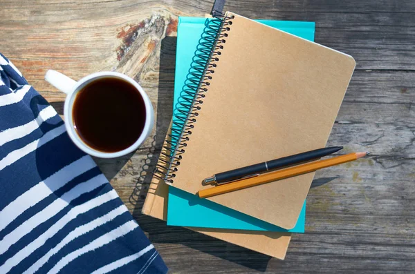 Una chica con una taza de café y se sienta en un banco del parque. Cuadernos para escribir y libros. Estudios, trabajo y concepto empresarial —  Fotos de Stock