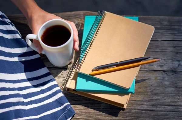 La chica con la mano sostiene una taza de café. Estudiar y trabajar en el parque —  Fotos de Stock