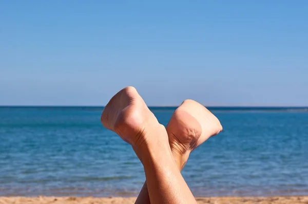 Beautiful woman 's legs on the beach sand — стоковое фото