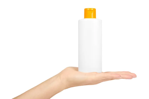 Flacone shampoo bianco in plastica con tappo arancione in mano isolato su sfondo bianco. Distributore di gel per la cura dei capelli. Contenitore con lozione corpo . — Foto Stock