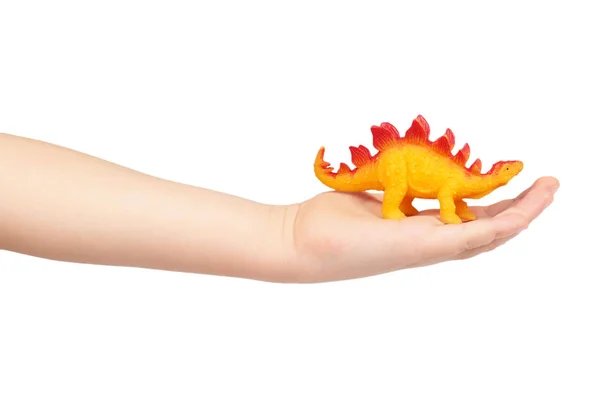 Brinquedo de borracha de dinossauro pré-histórico com mão de criança, isolado no fundo branco — Fotografia de Stock