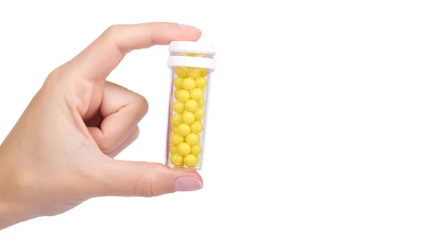 Geneeskunde fles met vitaminen in hand geïsoleerd op een witte achtergrond, transparante container met pillen, gele ballen. kopiëren van ruimte, sjabloon — Stockfoto