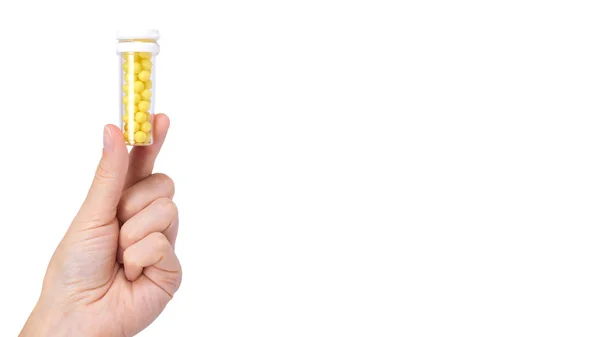 Garrafa de remédio com vitaminas na mão isolada em fundo branco, recipiente transparente com pílulas, bolas amarelas. espaço de cópia, modelo — Fotografia de Stock