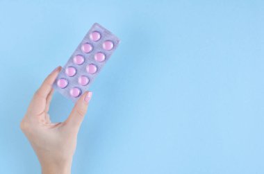 Mavi arka planda hap bileşimi olan bir el..