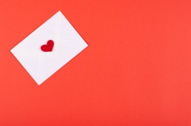 Kırmızı zemin üzerinde kırmızı kalp kompozisyonu olan kağıt zarf.
