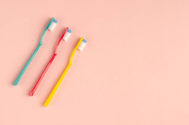 Pembe arka planda renkli diş fırçası kompozisyonu. Düz yatıyordu.