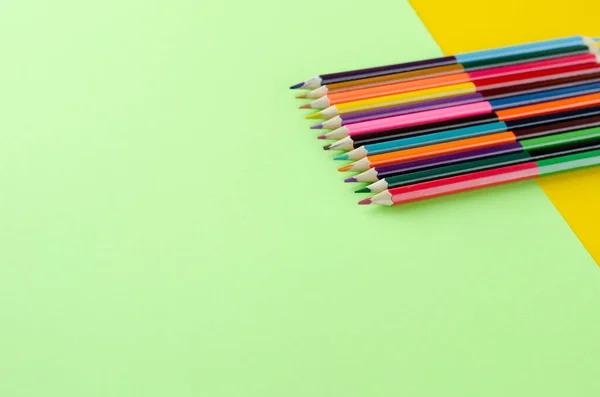 Composição de lápis coloridos em fundo amarelo e verde . — Fotografia de Stock