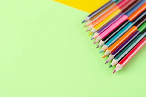 Composição de lápis coloridos em fundo amarelo e verde . — Fotografia de Stock