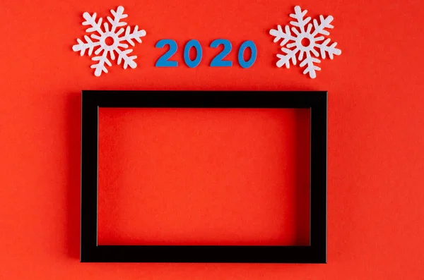 Nummer 2020, witte sneeuwvlokken en zwarte houten lijst compositie op rode achtergrond, Nieuwjaar en kerstvakantie. — Stockfoto