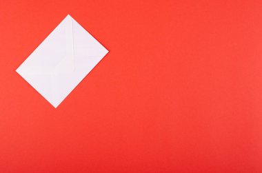 Kırmızı arka planda kağıt zarf kompozisyonu. Düz yatıyordu.