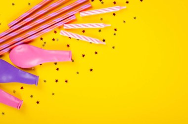 Sarı arka plan, parti ve kutlama dekorasyonunda renkli pipetler ve hava balonları kompozisyonu.