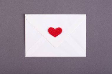 Koyu arkaplanda kırmızı kalp kompozisyonu olan kağıt zarf.