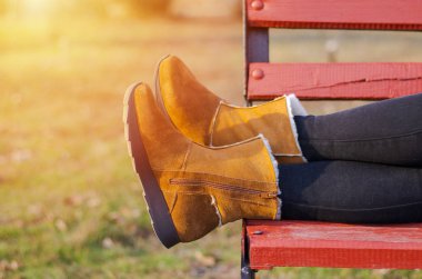 Kahverengi ayakkabılı kızların bacakları ahşap bir bankta yatıyor..