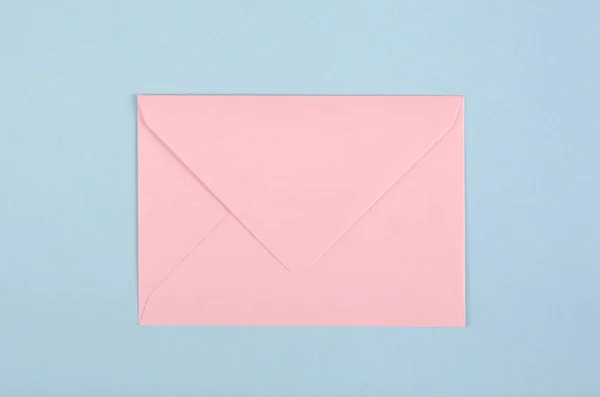 파란 배경 위에 분홍색 종이 봉투가 있다. — 스톡 사진