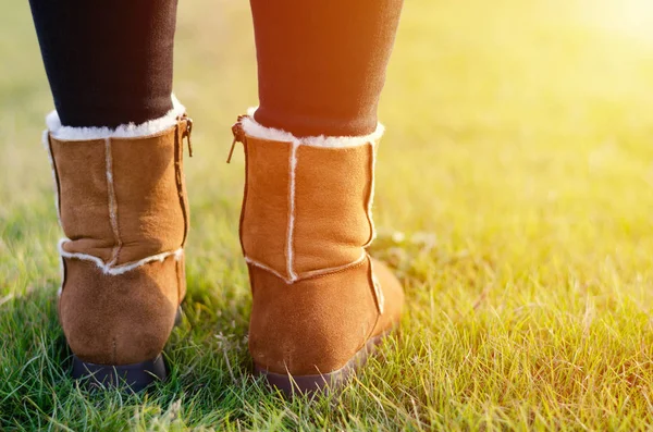 Les jambes des filles en bottes brunes se tiennent sur l'herbe. Voyager et randonner . — Photo