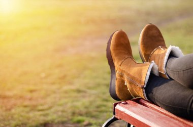 Kahverengi ayakkabılı kızların bacakları ahşap bir bankta yatıyor..