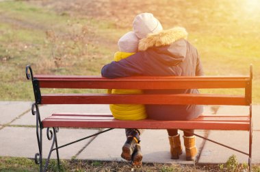 Anne, çocuğu tahta bankta kucaklıyor. İlgi ve sevgi.