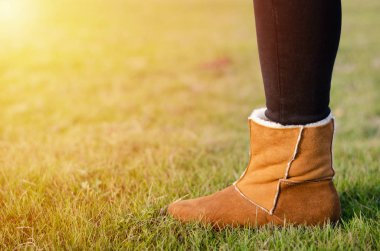 Kahverengi çizmeli kızların bacakları çimlerin üzerinde duruyor. Seyahat ve yürüyüş..