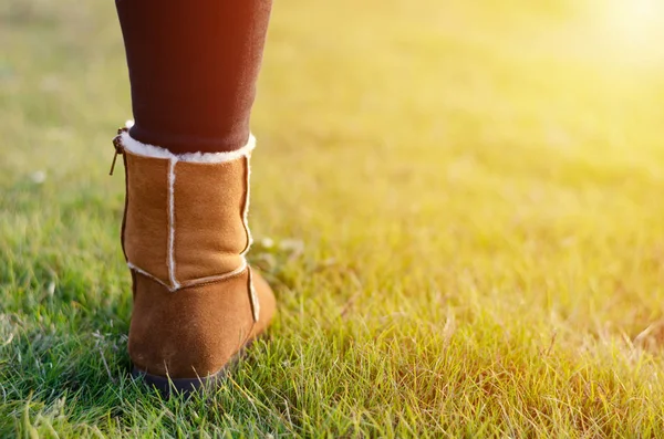 A barna csizmás lányok lábai a fűre állnak. Utazás és túrázás. — Stock Fotó