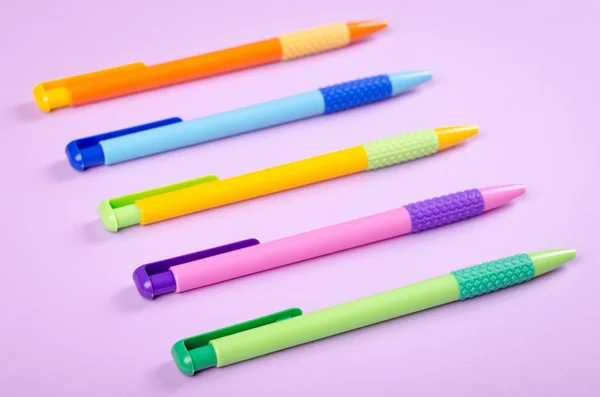 Bolígrafos de diferentes colores, bolígrafo escolar en la composición de fondo púrpura. —  Fotos de Stock