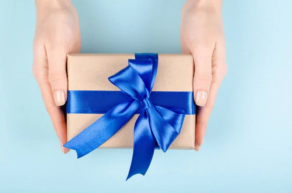 Mãos com caixa de presente na composição de fundo azul, presente com fita e arco. — Fotografia de Stock