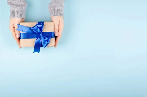 Mãos com caixa de presente na composição de fundo azul, presente com fita e arco. — Fotografia de Stock