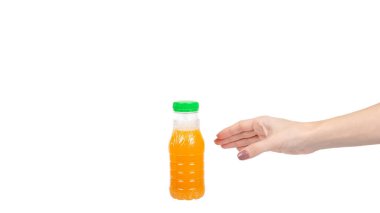 Hand with orange juice in little plastic bottle for kids. Healthy drink. Isolated on white background. Copy space, template.
