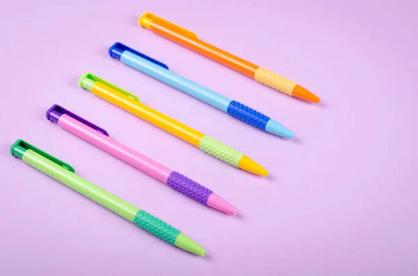 Bolígrafos Diferentes Colores Bolígrafo Escolar Composición Fondo Púrpura Plano Vista — Foto de Stock