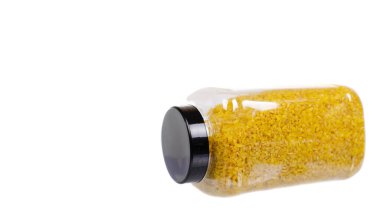 Plastik kabın içinde çiğ sarı bulgur taneleri, sağlıklı tahıllar, tam buğday. Beyaz arka planda izole edilmiş. Uzayı kopyala, şablon.