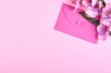 Zarf ve çiçekler pembe arka plan kompozisyonu. Düz bir fotoğraf..