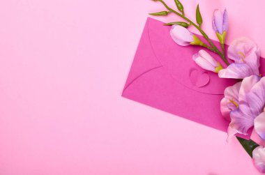 Zarf ve çiçekler pembe arka plan kompozisyonu. Düz bir fotoğraf..