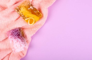 Spa fikri, mor arka planda havlu ve sabun kompozisyonu. Düz yatıyordu.