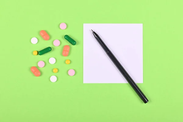 Medical pills, recipe on green background, flat lay, overhead view image.