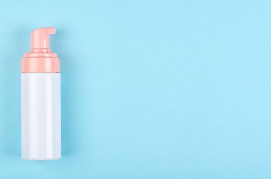 Mavi arka planda dezenfektan şişesi olan bir el. Düz, yukarıdan görüntü. Uzayı kopyala, şablon.